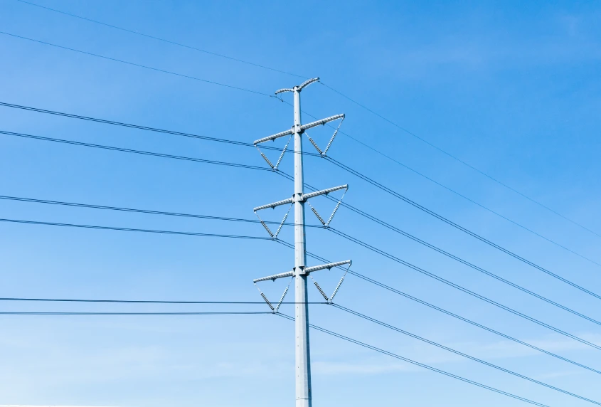 Representative electricity transmission monopole and overhead lines against a blue sky; not identified as the newly awarded Australian project.