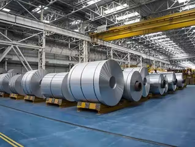 Steel coils stored inside an industrial factory — representative image